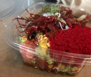 A colorful Poke bowl with bigeye tuna, roe, sweet onion, avocado, sea salt, sesame brittle, cucumber, mixed seaweed and classic Hawaiian sauce.